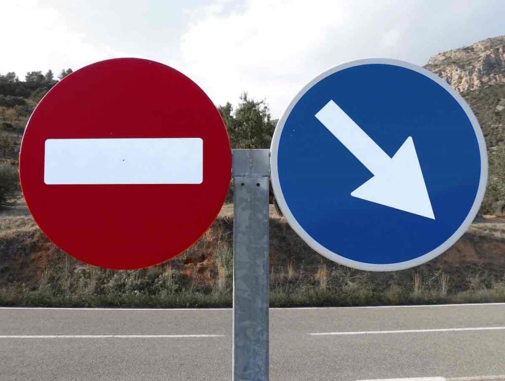Deux panneaux de signalisations. Un sens interdit et obligation de direction. La motivation par obligation pour Vaincre la procrastination.