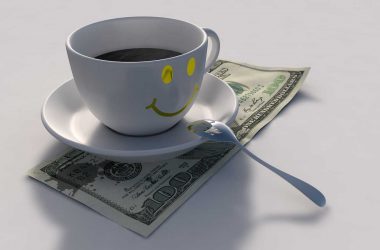 Comment faire des économies de façon intelligente. Une tasse de café souriante sur un billet de 100 dollars.