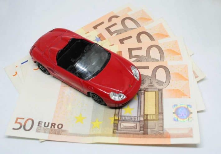 Économiser sur sa voiture. Le budget auto. Une miniature de voiture sur des billets de banque.