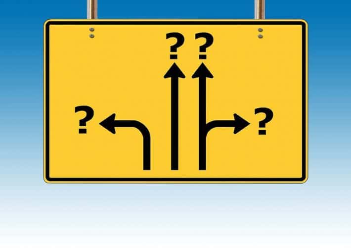 Choisir de devenir riche, c'est possible ? Un panneau de signalisation avec des directions se finissant par un point d'interrogation.