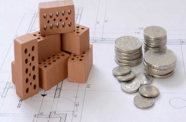 Programme d’épargne. Des briques de constructions sur un plan avec de la monnaie.