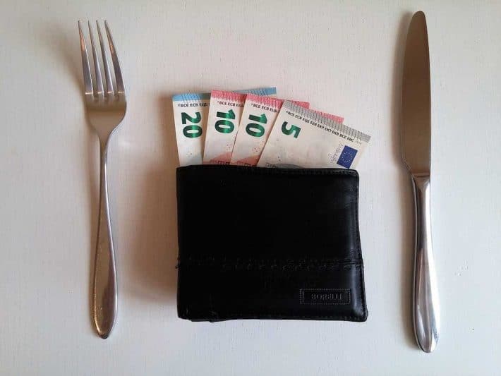 Comment être riche. Portefeuille avec des billets de banque entourè d'un couteau et d'une fourchette.