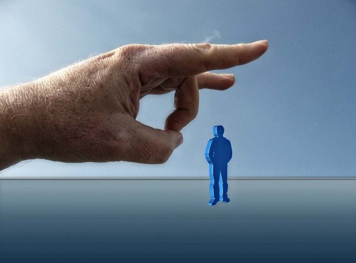 Réforme chômage 2019. Une main géante mettant une pichenette à un humain.